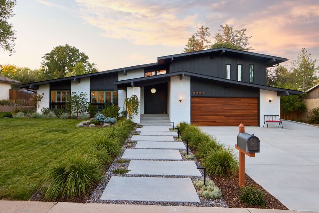 Modern single-story home with black and white exterior, landscaped yard, and inviting walkway.