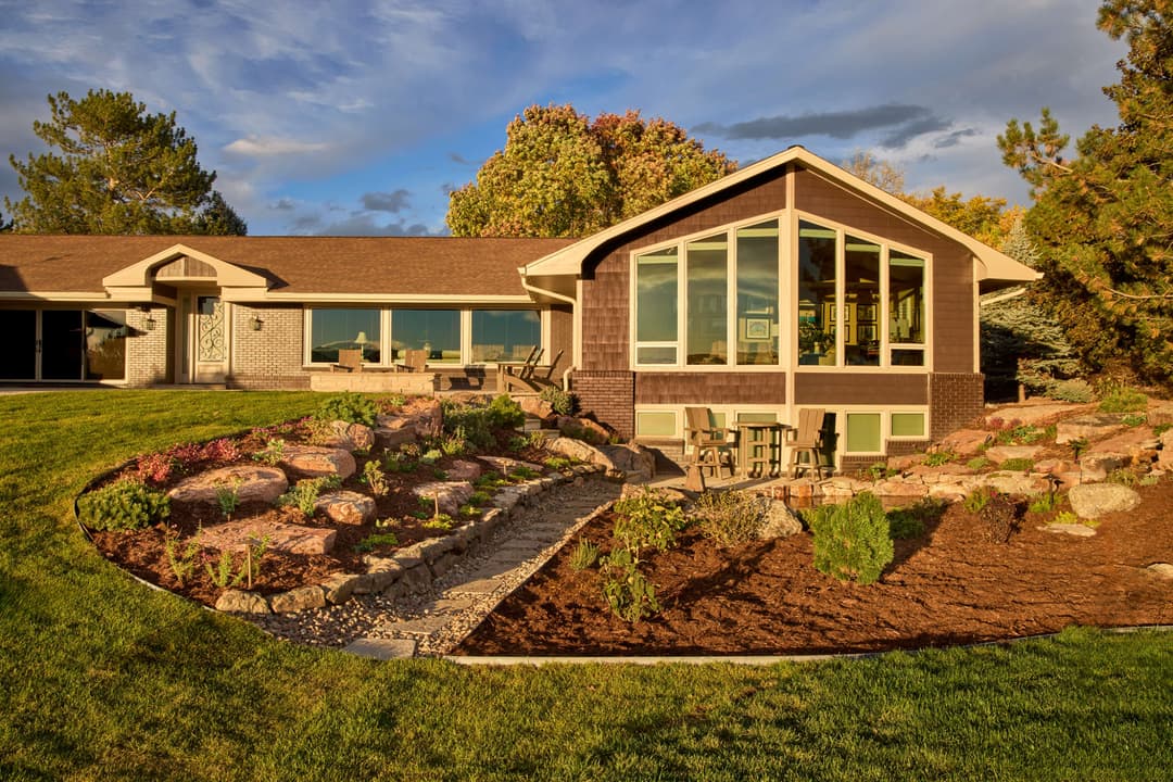 Modern home with large windows, landscaped yard, and evening sky backdrop.