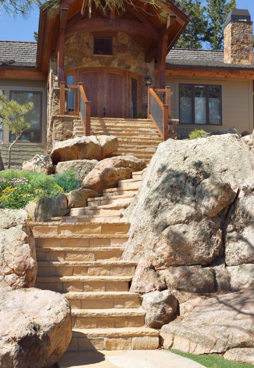 Stunning stone staircase leading to a rustic home surrounded by natural rock features.