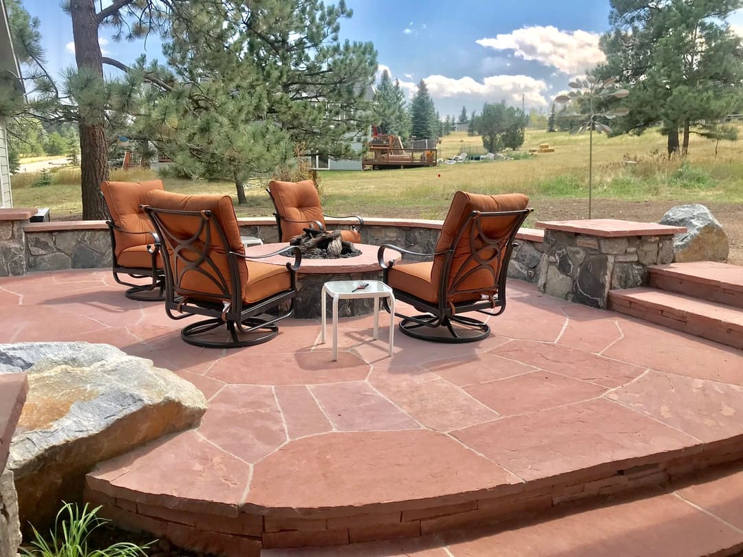 Cozy outdoor seating area with swivel chairs and stone patio overlooking lush landscape.