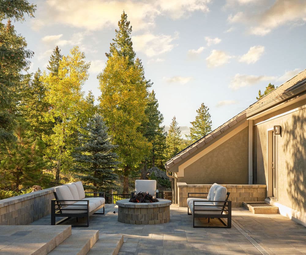 Cozy outdoor patio with fire pit, seating, and vibrant autumn trees in the background.
