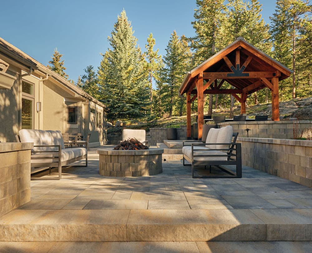 Cozy outdoor living space with seating, fire pit, and gazebo surrounded by trees.
